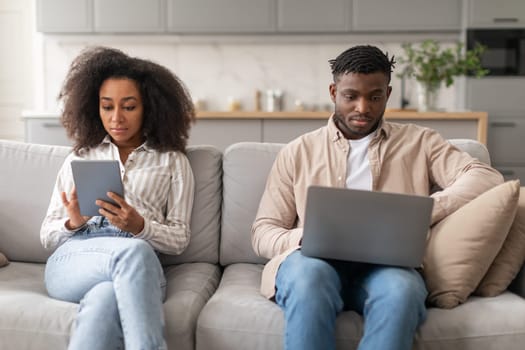 Modern millennial black couple browsing on laptop and tablet indoor