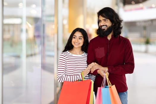 Happy young indian woman walking by mall with her boyfriend