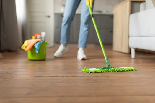 Mopping hardwood floor with cleaning supplies nearby