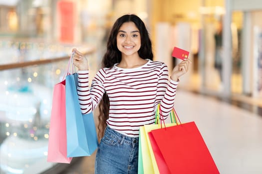 Positive young indian woman enjoying unlimited shopping at mall