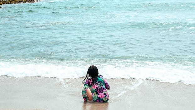Happy girl sitting on the water's edge in the beautiful beach of San Bartolo south of Lima - Peru. Summer Vacation.