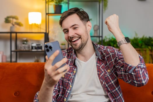 Surprised excited man winner holding smartphone reading good news amazed by online bet bid game win