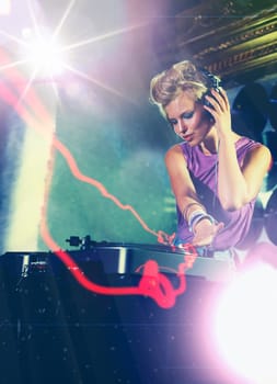 Woman, dj and turntable with headphones for music on stage with lens flare, mixing and gig at rave party for entertainment. Female sound mixer, artist and musician with record player for playlist