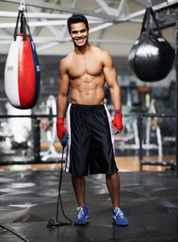 Man, portrait and equipment in gym for boxing, training and keeping fit for competition. Male person, mma fighter and exercise in fitness centre for wellness, health and maintain strength for match