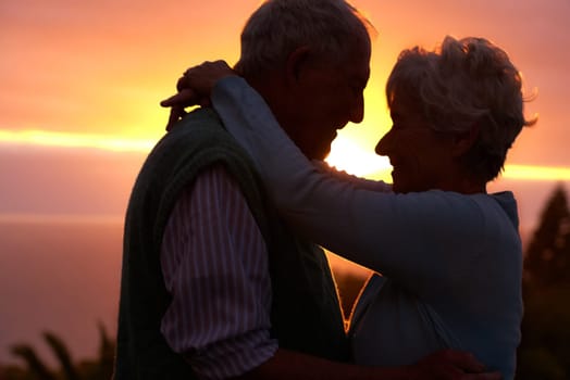 Sunset, elderly couple and hug outdoor, love and bonding for connection together in nature. Man, woman and embrace for care, romance and support for commitment to relationship in retirement on date