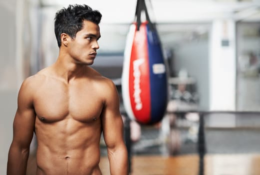 Boxing, training and man in gym for exercise, practice and fitness for health. Personal trainer, serious expression and thinking with confidence for workout, planning and vision with shirtless body