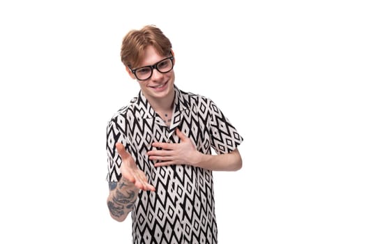 young handsome red-haired guy in glasses dressed in a summer shirt holds out his hand for a handshake
