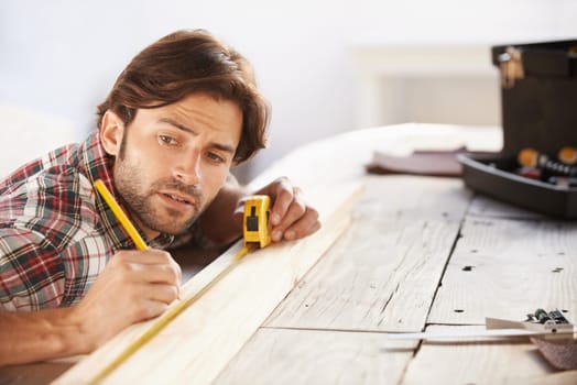 Carpenter, wood and measuring tape with man for DIY or renovation in a workshop. Craftsman, timber or measure with object for scale with construction and male person contractor with woodwork