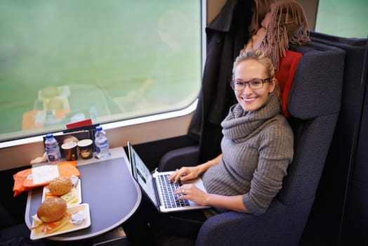 Woman, train and portrait with laptop or internet for commute journey with travel, communication or transportation. Female person, face and meal in coach in Canada or online, research or passenger