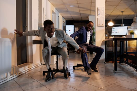 Playful businessmen riding desk chair during sports race