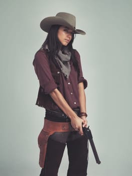 Woman, fashion and cowboy clothes with gun in studio, western character and costume isolated on white background. Wild west style, pistol for outlaw cosplay and vintage apparel in a portrait.