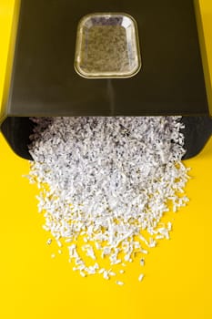 Shredded white paper on light yellow background close up