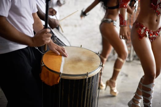 Drummer, playing and music with percussion by stage, dancers and rhythm of artist with talent in band. Brazilian people, samba or performing in group as professional musician or costume for live show