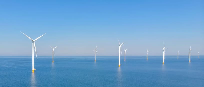 Wind turbines off the coast create electricity in the azure sea