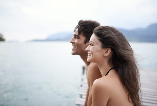 Couple, jetty and travel to ocean on adventure, love and relax by water on summer holiday. People, swimwear and bonding for relationship in outdoor, support and smile on weekend trip to sea or nature