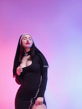 A nun girl in a sexy dress defiantly poses naked on a neon background of a copy paste
