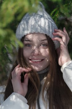 Portrait of happiness teenager girl looking at camera, raised hands to face in winter forest