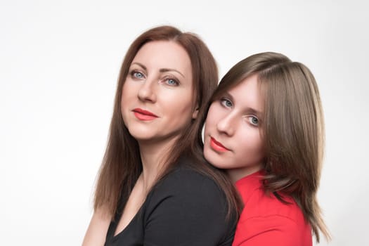 Portrait of mother and daughter looking at camera. Mom in black t-shirt and teenager in red