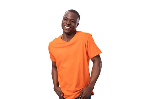 young energetic cheerful american man dressed in a basic orange t-shirt rejoices and smiles on a white background with copy space