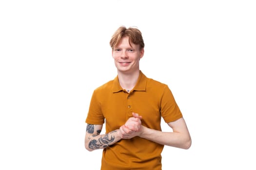 young successful red-haired guy dressed in an orange t-shirt with a tattoo on his arm