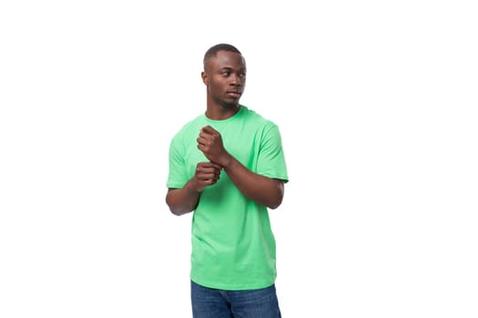young well-groomed african man in light green t-shirt and jeans isolated on white background