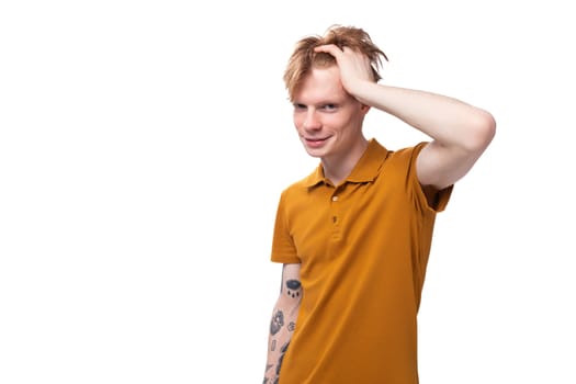 portrait of handsome young redhead caucasian male student with tattoo dressed in mustard t-shirt