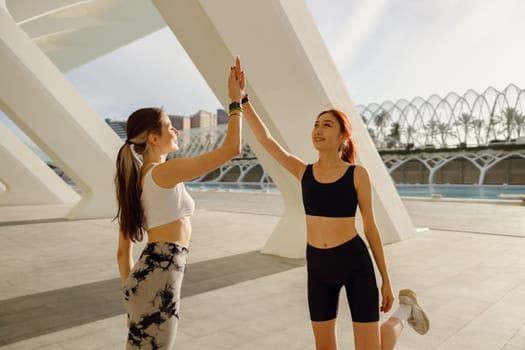 Sporty women greeting together outdoor doing gesture of shake hand after exercising