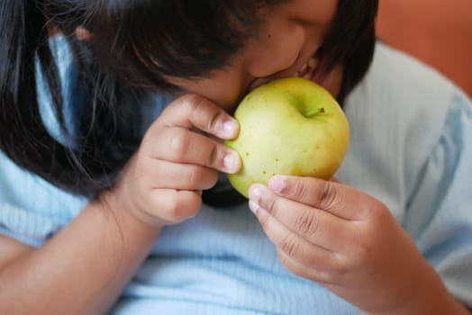 Girl biting and eating green apple