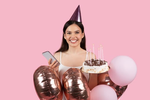 Happy woman with birthday cake, balloons and phone