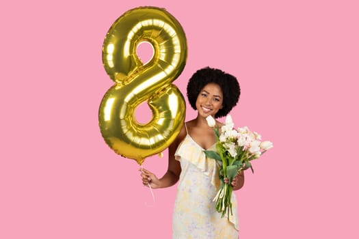 Joyful woman with curly hair celebrating with a golden number 8 balloon
