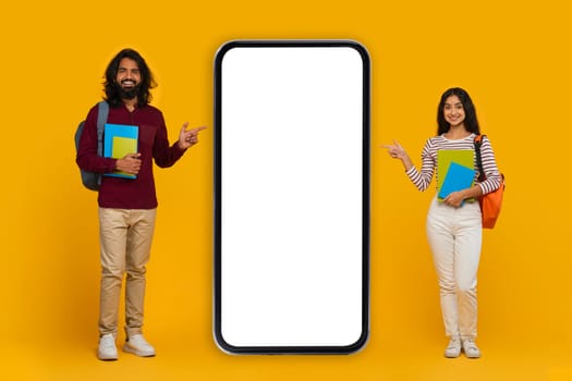 Positive indian students pointing at big phone with white screen