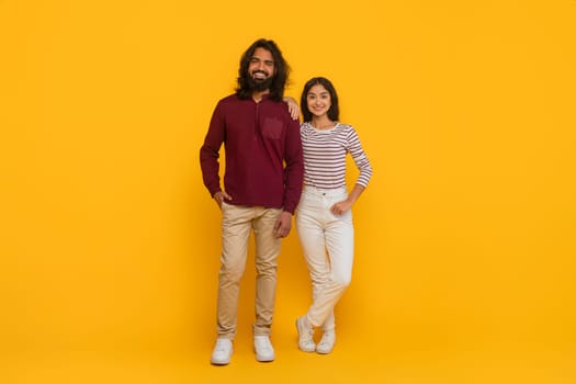 Cool indian man and woman friends posing on yellow