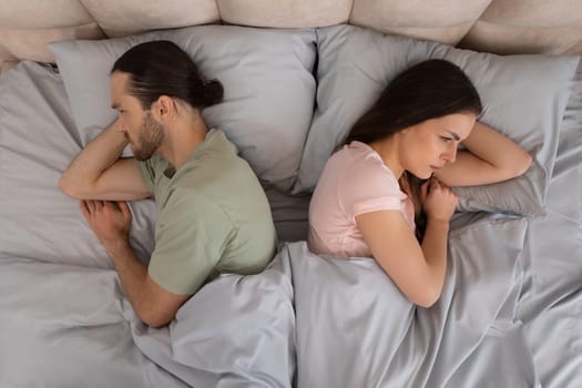 Couple in bed facing away from each other, upset