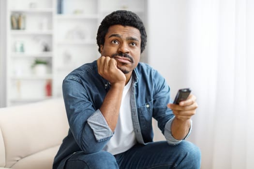 Portrait Of Bored Young Black Man Watching TV At Home