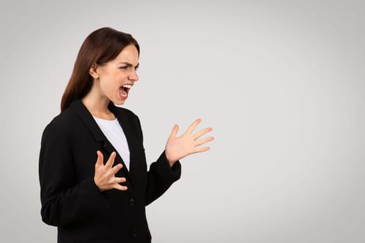 Angry businesswoman shouting with a fierce expression, her hands open in a defensive or confrontational manner