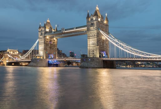 View of famous Tower bridge and skyline with reflections in the river thames just after sunset.