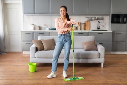 Woman with mop in stylish kitchen, looking content