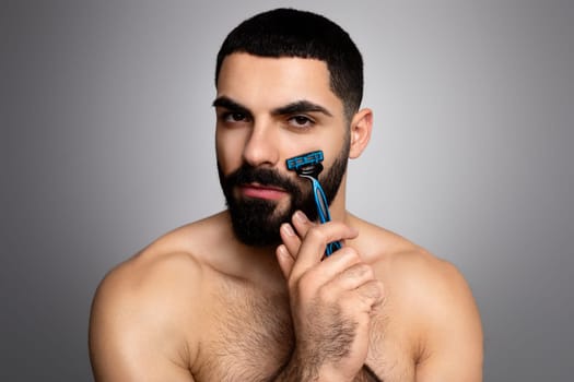 Handsome young muscular arab man shaving his beard
