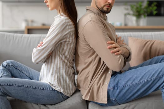 Couple in disagreement, sitting back to back on couch