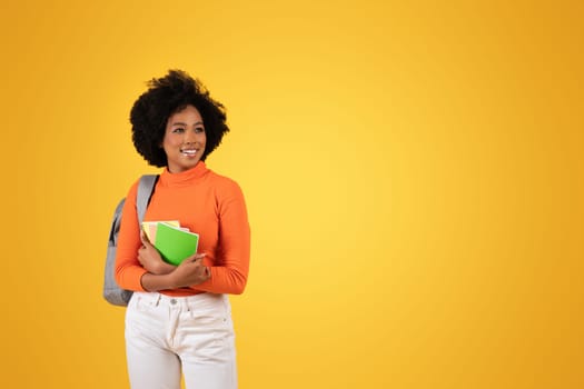 A cheerful young student with a natural afro hairstyle stands