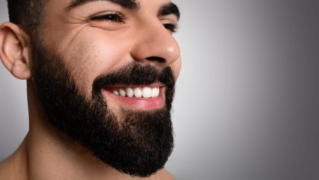 Closeup of handsome smiling middle eastern man posing on grey