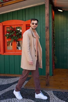 Handsome man in trendy outfit walking near Christmas house