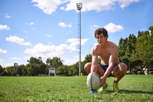 Man, rugby ball and ready to kick on field with thinking, aim and target for challenge, training and fitness. Athlete, vision and prepare for sports, game or workout on grass field with wellness