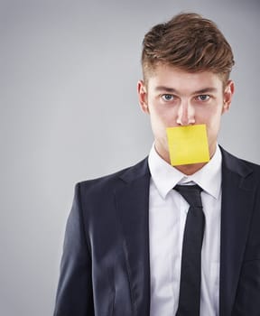 Business man, sticky note and mouth in portrait for silence, reminder and studio by white background. Person, employee and corporate workout with paper on lips for compliance, censorship and quiet