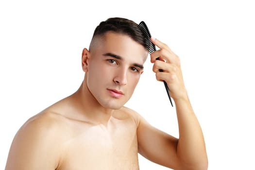 Portrait of handsome young man combing his hair on white background