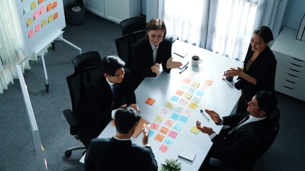 Top view of business people brainstorm idea by using sticky notes while planning marketing strategy at meeting room. Group of diverse team discuss about financial plan. Teamwork concept. Directorate.