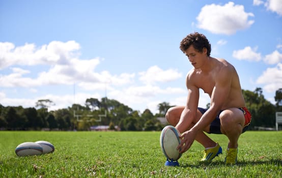 Man, rugby ball and ready to kick on grass with thinking, aim and target for challenge, training and fitness. Athlete, person and prepare for sports, games and workout on field with vision for goal