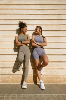Smiling female sportswomen with crossed hands have a rest after morning jogging outdoors