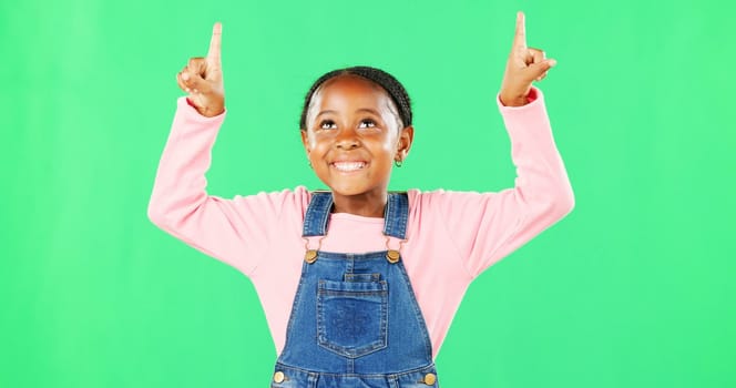 Kids, pointing and a black girl on a green screen background in studio for marketing a product. Children, portrait and advertising with a cute little female child showing space on chromakey mockup