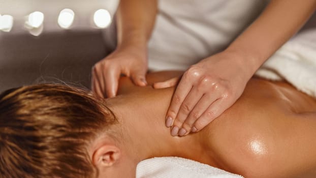 Masseur making therapeutic neck massage for girl